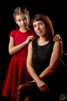 Happy family mom and daughter in the studio on a black background. The concept of love, childhood.