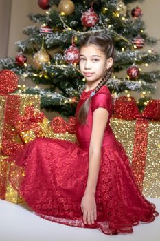 Beautiful little girl near the Christmas tree. The concept of family holidays, children's emotions.