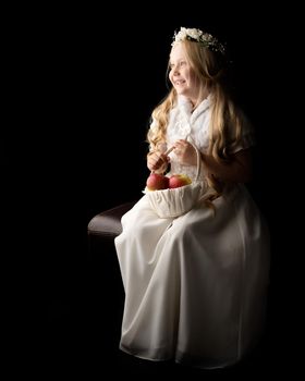 Little girl with a basket of apples. The concept of a healthy diet, happy childhood. On a black background.