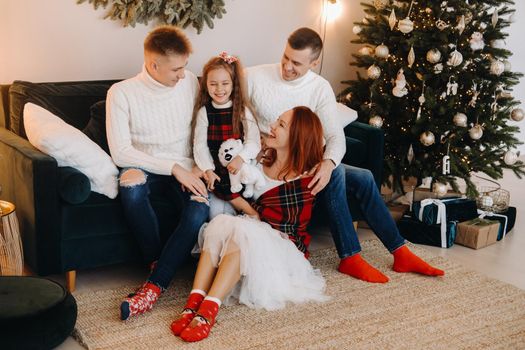 Close-up portrait of a happy family sitting on a sofa near a Christmas tree celebrating a holiday.