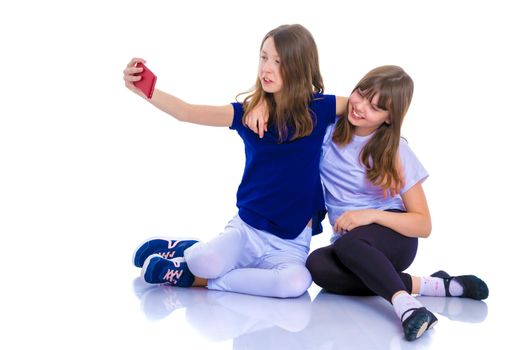 Two happy smiling girls make a self-portrait on a smartphone. The concept of people and technology. Isolated on white background.