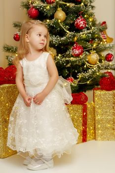 Beautiful little girl near the Christmas tree. The concept of family holidays, children's emotions.