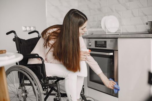 Disabled woman cleaning the kitchen stove. Impaired people concept.