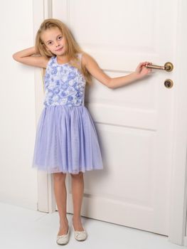 A nice little girl is standing by the door. The concept of family happiness and a home.