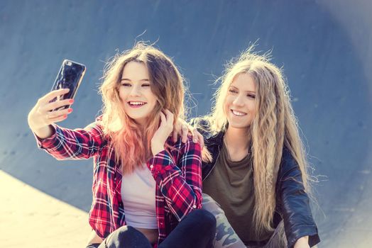 Happy girl friends taking a selfie on a summer day. Two teen girl having fun while making selfie on smartphone