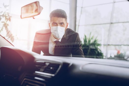 Man car dealer wearing protective medical mask on his working place, coronavirus prevention concept