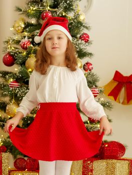 Beautiful little girl near the Christmas tree. The concept of family holidays, children's emotions.