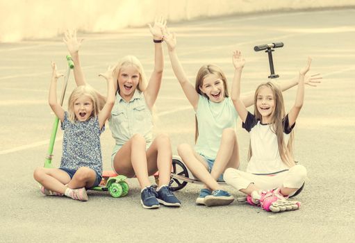 Pretty little girls smiling sitting on the ground with joyfully raised hands