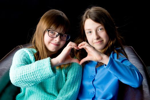 Two school girls folded their hands in the shape of a heart. Concept of friendship, happy people.
