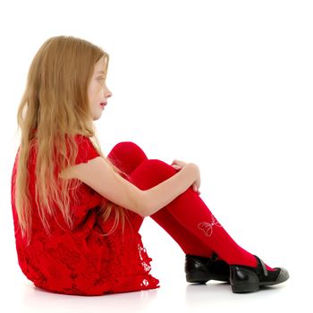 Cute girl posing on the floor in the studio. Hugs his knees. Isolated on white background. The concept of beauty and fashion