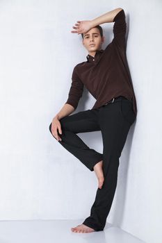 Young male fashion model posing in a casual outfit on grey background