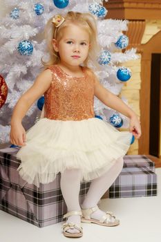 Beautiful little girl near the Christmas tree. The concept of family holidays, children's emotions.