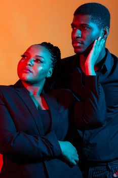 Portrait of young african american couple in love posing at studio dressed in classic clothes. Neon light