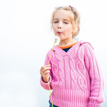 6-year-old beautiful girl blowing dandelion