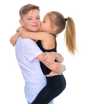 Charming little girl hugging a tall boy with blond hair. A romantic couple is happy with the joint time brought. A happy sister hugs her brother. The concept is a happy childhood. Isolated on white background.