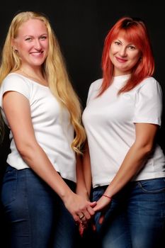 Young, beautiful women in white T-shirts are holding hands.