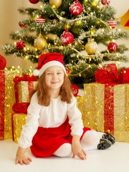 Beautiful little girl near the Christmas tree. The concept of family holidays, children's emotions.