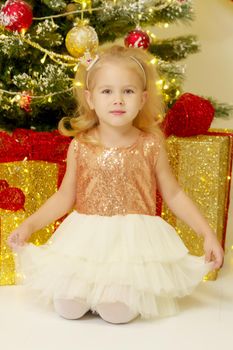 Beautiful little girl near the Christmas tree. The concept of family holidays, children's emotions.