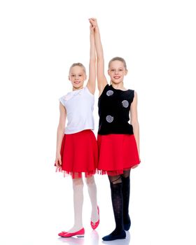 Two cheerful little girls are dancing in the studio on a white background. The concept of a children's dance school, happy people. Isolated.
