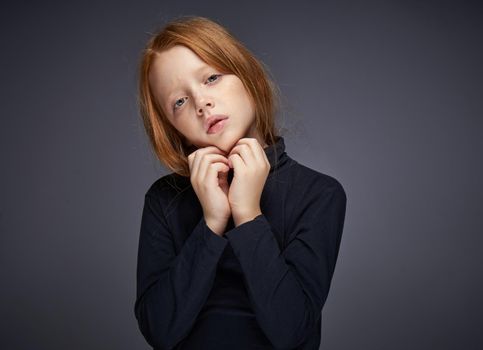 red-haired girl with freckles on her face in a black sweater posing. High quality photo