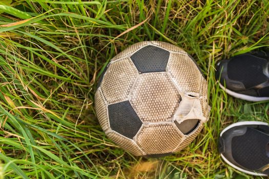 Old Soccer ball on the green grass, top view.