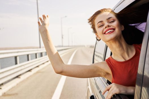 cheerful woman peeking out of the car window trip road travel. High quality photo