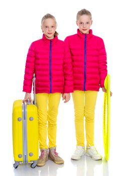 Two cute little girls with large suitcases prepared for the journey. Isolated on white background.