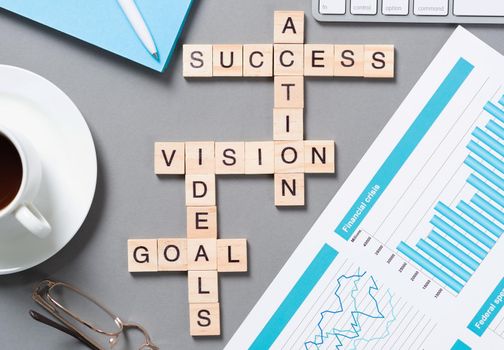 Business motivation concept with words from cubes. Still life of office workplace with crossword. Flat lay grey surface with pc keyboard and cup of coffee. New strategy planning and management