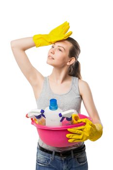 attractive beautiful young woman in yellow rubber gloves holding pink basin with detergents over white