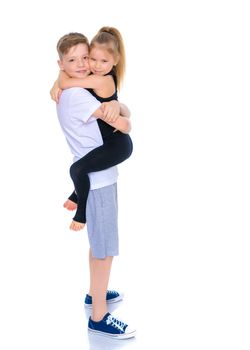 Charming little girl hugging a tall boy with blond hair. A romantic couple is happy with the joint time brought. A happy sister hugs her brother. The concept is a happy childhood. Isolated on white background.