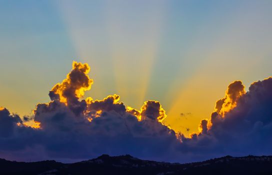 Background from a beautiful sunset with clouds and sunlights over mountanous coast. High quality photo