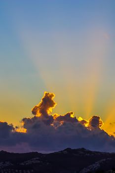 Background from a beautiful sunset with clouds and sunlights over mountanous coast. High quality photo