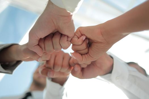 Close up of young businessman and businesswoman making a fist bump on building background