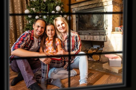 Big family with three children celebrating Christmas at home. Festive dinner at fireplace and Xmas tree. Parent and kids eating at fire place in decorated room. Child lighting advent wreath candle