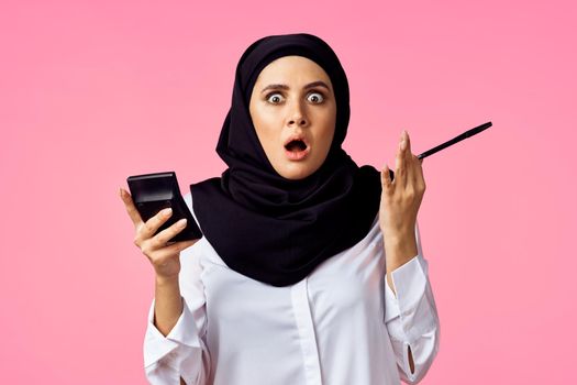 muslim woman with calculator and finance money pink background. High quality photo