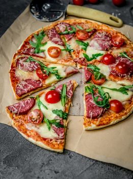 homemade pizza with salami, cherry tomatoes and rucola