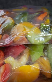 Sliced ripe bell pepper fruits in cellophane bags, prepared for freezing and long-term storage in the freezer compartment of the refrigerator. Front view, close-up.