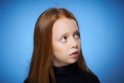 redhead girl with freckles on her face posing close-up blue background. High quality photo