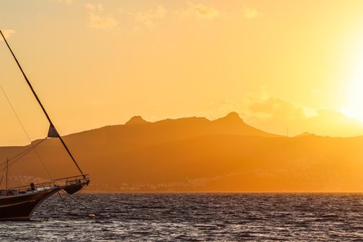 Beautiful sunset on the Aegean Sea with mountains and a sailboat. Seascape, travel and nature concept. High quality photo