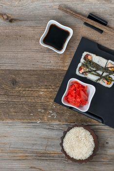 rolls on tray and a bowl of rice on wooden table with text space top view