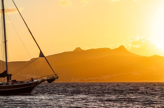 Beautiful sunset on the Aegean Sea with mountains and a sailboat. Seascape, travel and nature concept. High quality photo