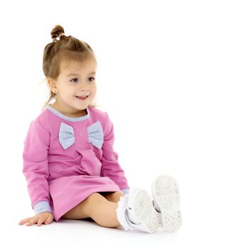 Beautiful little girl is sitting on the floor in the studio. The concept of a happy childhood, beauty and fashion. Isolated on white background.