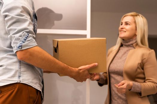 Happy deliverer carrying packages while making home delivery to his customer