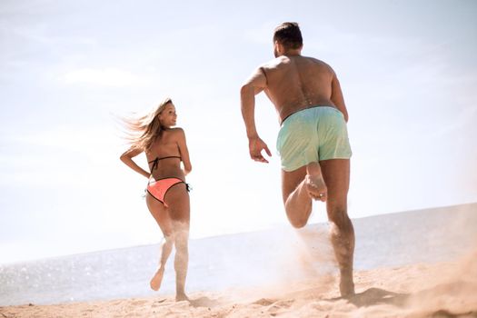 Happy lovers playing with each other on the beach.