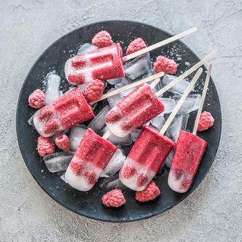 Homemade raspberry ice cream on a stick on a concrete background