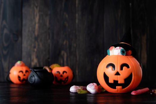 Halloween concept. Halloween party jack o lanterns pumpkins full of sweets on black wooden background