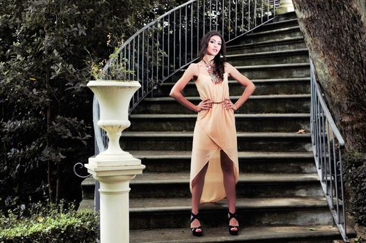 Portrait of a beautiful young woman, model of fashion, in a garden stairs.