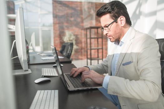 behind the glass.serious businessman typing on a laptop. business concept