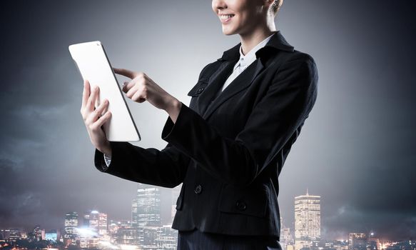 Businesswoman using tablet computer. Double exposure concept with night city and woman in business suit. Real estate investment. Digital technology in property management and development company.