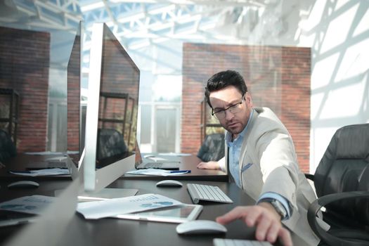 behind the glass.serious businessman sitting at the office table